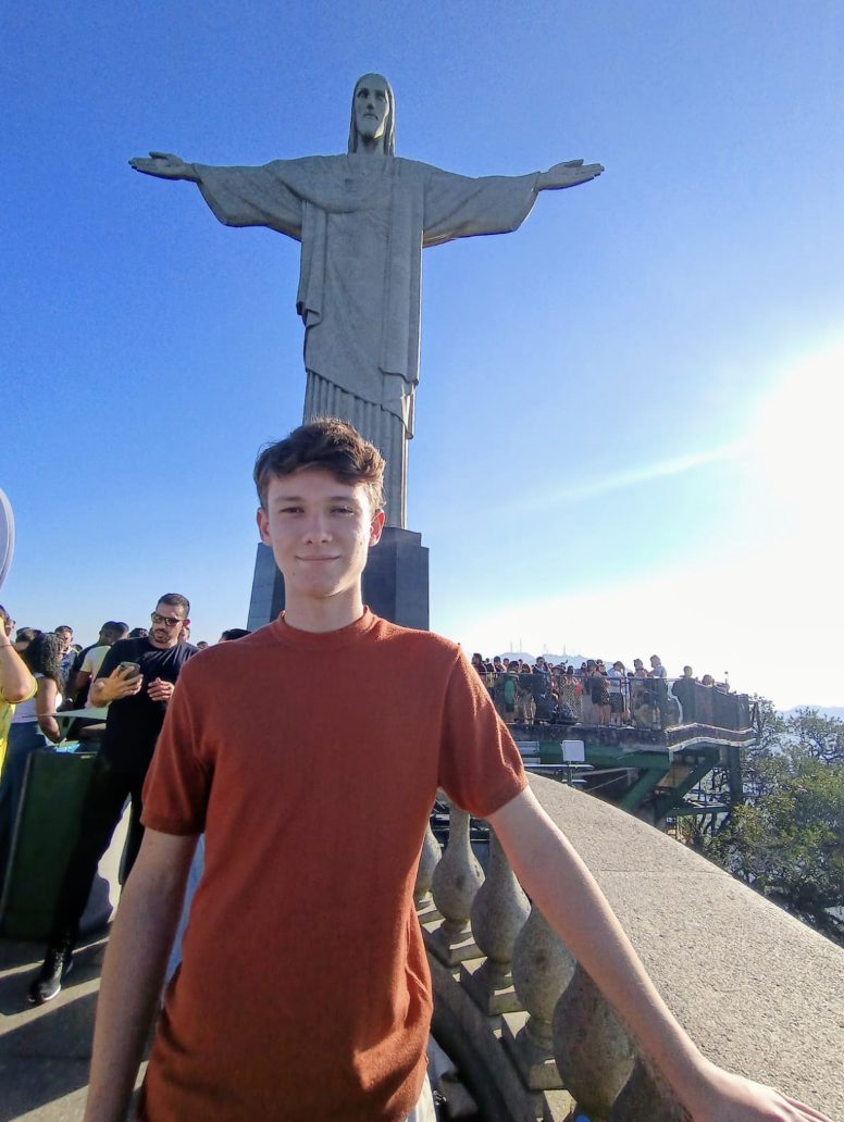 Cliente posando em frente ao Cristo Redentor, com céu azul